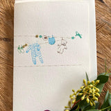 Beautiful handmade Baby Boy Washing Line card by Elena Deshmukh. Printed on luxury sustainable textured card with delicate artisan detail.