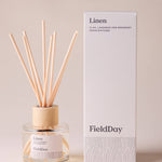 FieldDay Linen reed diffuser with flax, lavender and rosemary fragrance in a glass bottle with wooden cap and natural reeds.