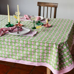 Green hand block printed cotton tablecloth with pink fan motifs and striped border styled on an elegant dining table.