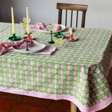 Green hand block printed cotton tablecloth with pink fan motifs and striped border styled on an elegant dining table.