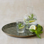 Round green serving tray with decorative peacock feather-inspired pattern