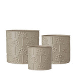 A set of three cream-colored metal pots with a floral pattern, designed for planting.
