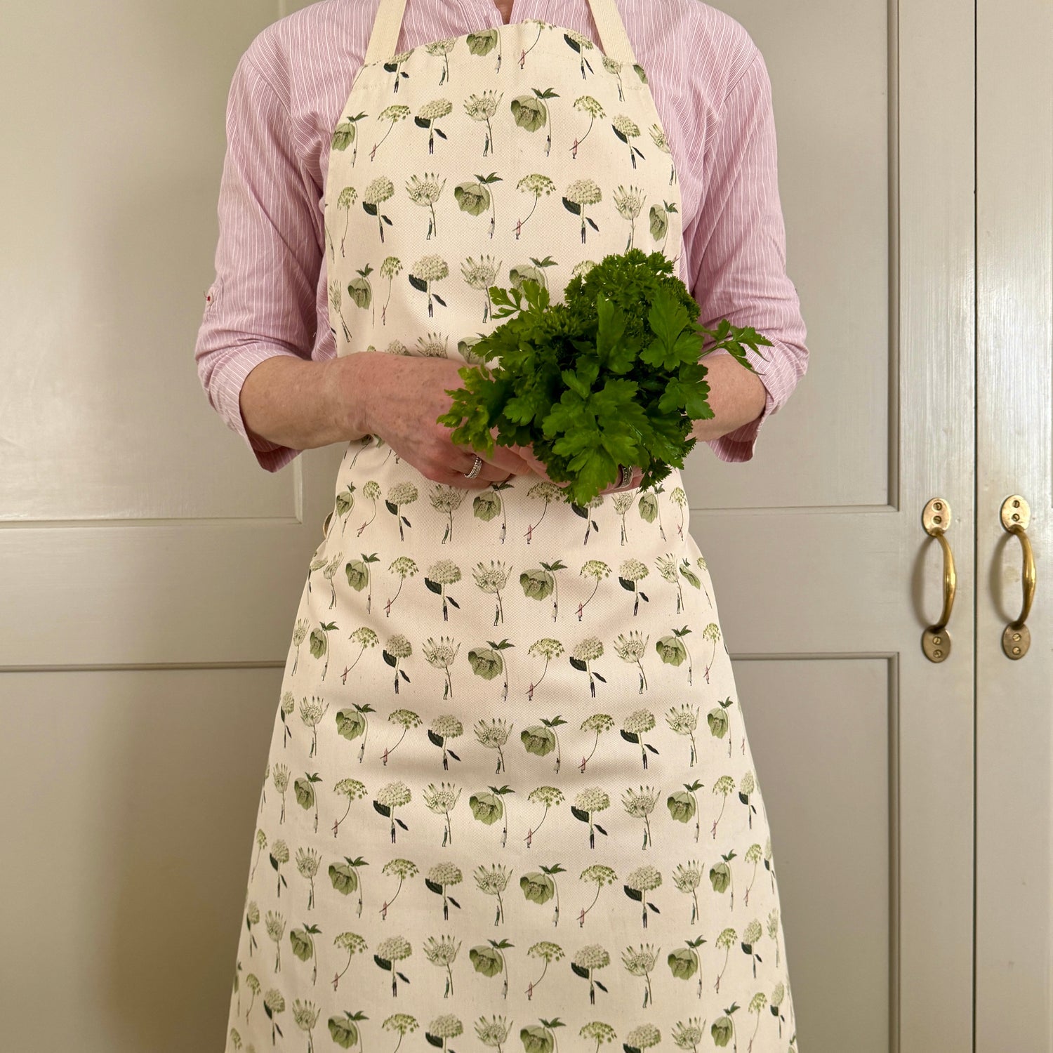 In Bloom Green Flowers cotton apron featuring botanical illustrations of hellebore, astrantia, ammi and hydrangea, handmade in England.