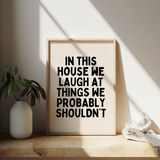 Funny black and cream typography wall art print featuring the quote ‘In This House We Laugh At Things We Probably Shouldn’t’. Perfect for modern family homes.