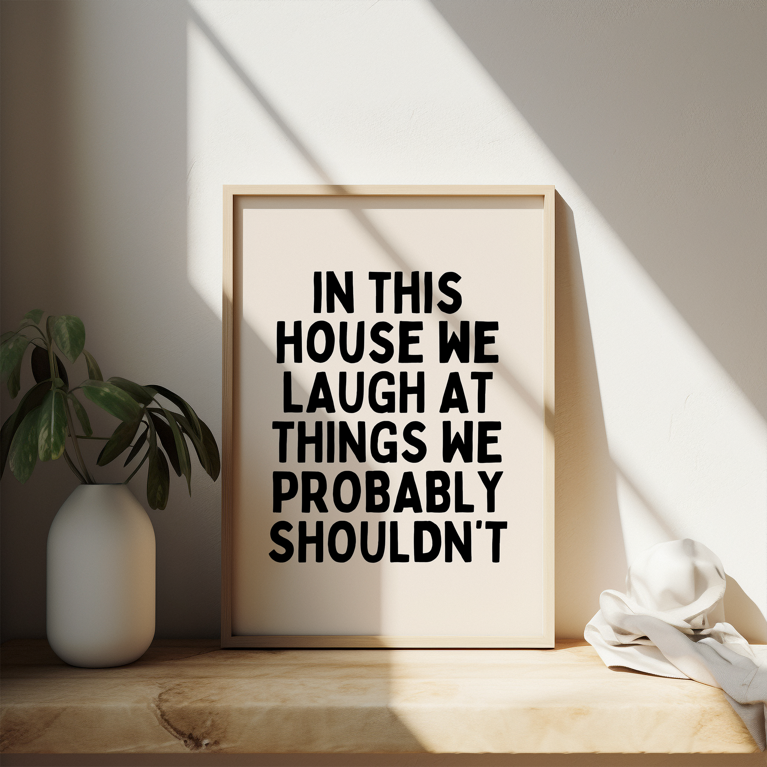 Funny black and cream typography wall art print featuring the quote ‘In This House We Laugh At Things We Probably Shouldn’t’. Perfect for modern family homes.