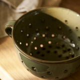 Ithaca Moss green stoneware berry bowl and colander with perforated sides, organic shape and practical handles.