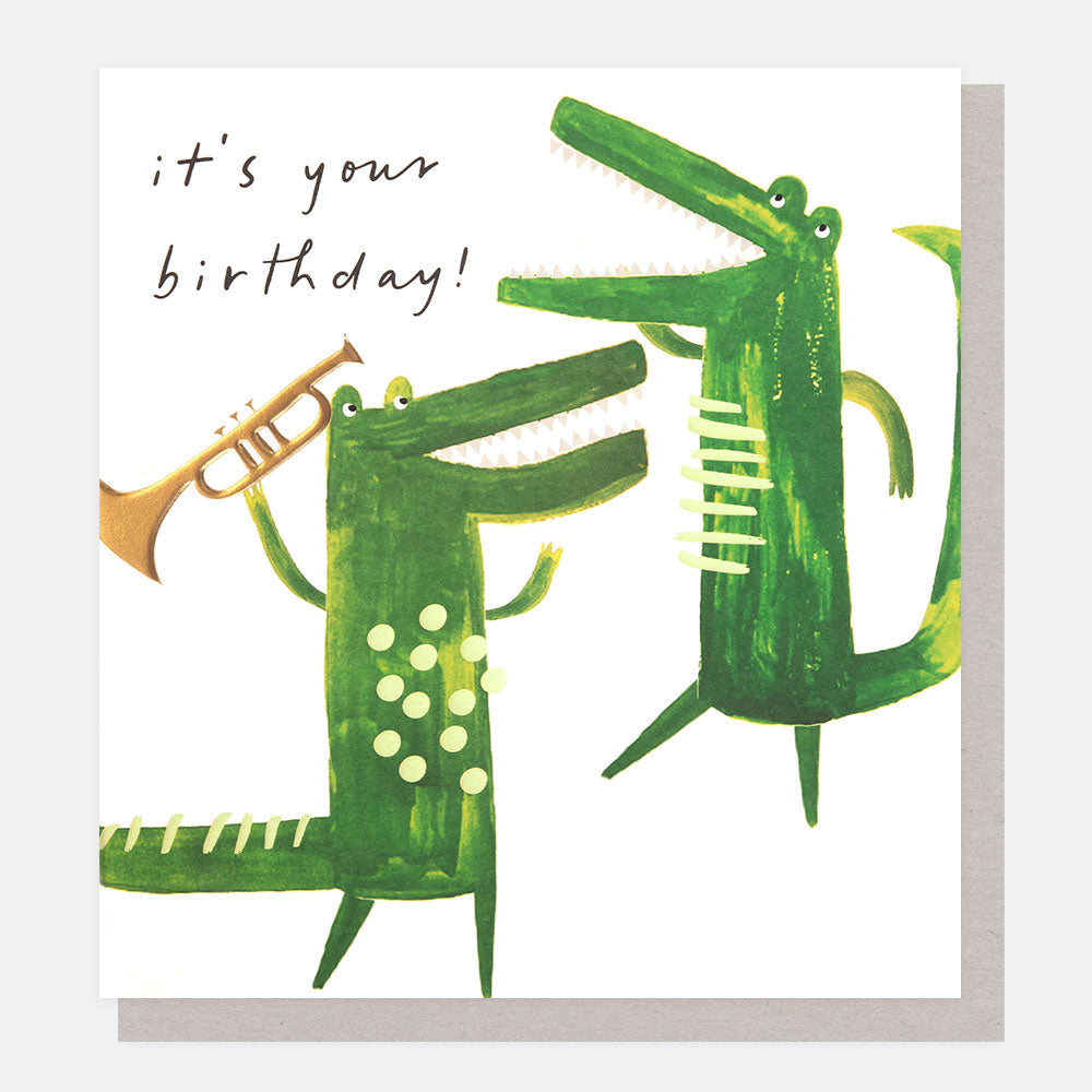 It’s Your Birthday card featuring a dancing crocodile playing a trumpet with gold foil and embossed detailing.