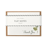 A flat note card with a 'Thank You' message, featuring a green hellebore design, enclosed in a clear bio-film packaging with a kraft paper envelope.