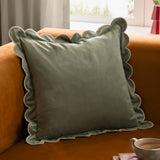 Lil Scallop velvet cushion in green and natural with a soft velvet finish, scalloped edge and contrast trim, styled on a contemporary sofa.