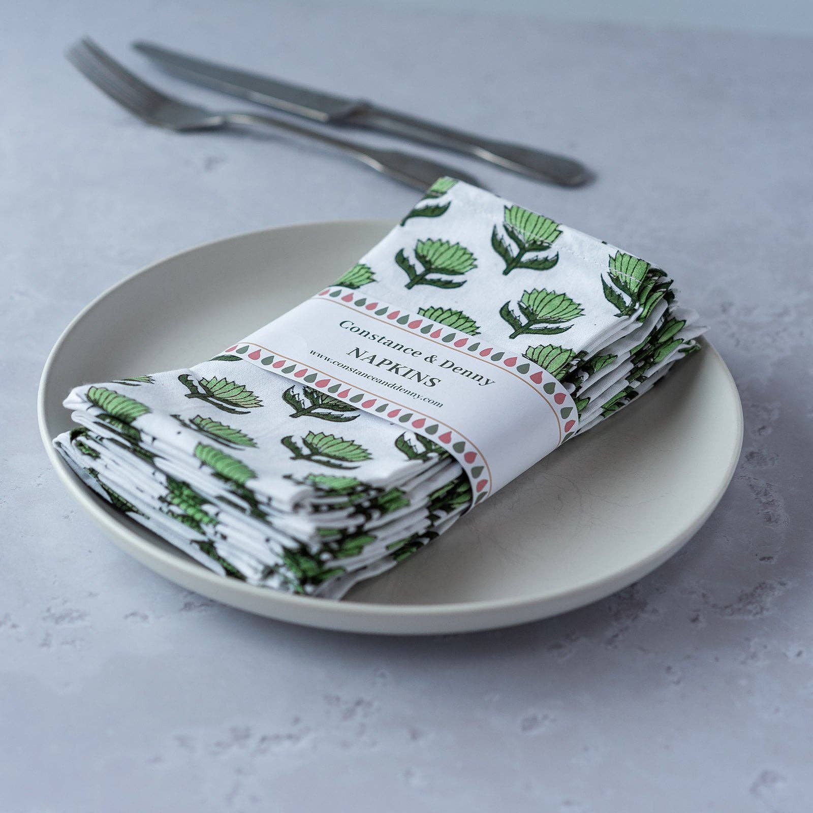 Hand block-printed Lotus Flower cotton napkins in soft modern colours styled on an elegant dining table.