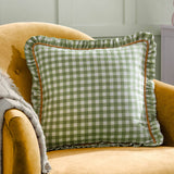 Maude gingham cotton cushion with reversible checked design, piped frilled trim and hidden zip, styled on a country-style sofa with layered cushions and throws.
