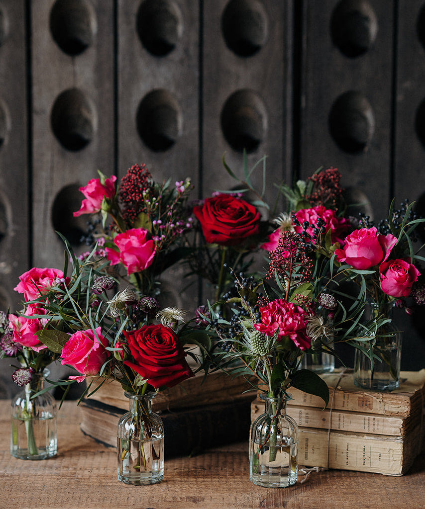 Merry Little Kisses Christmas bud vase collection with red and pink seasonal flowers, berries and winter foliage arranged in individual glass vases