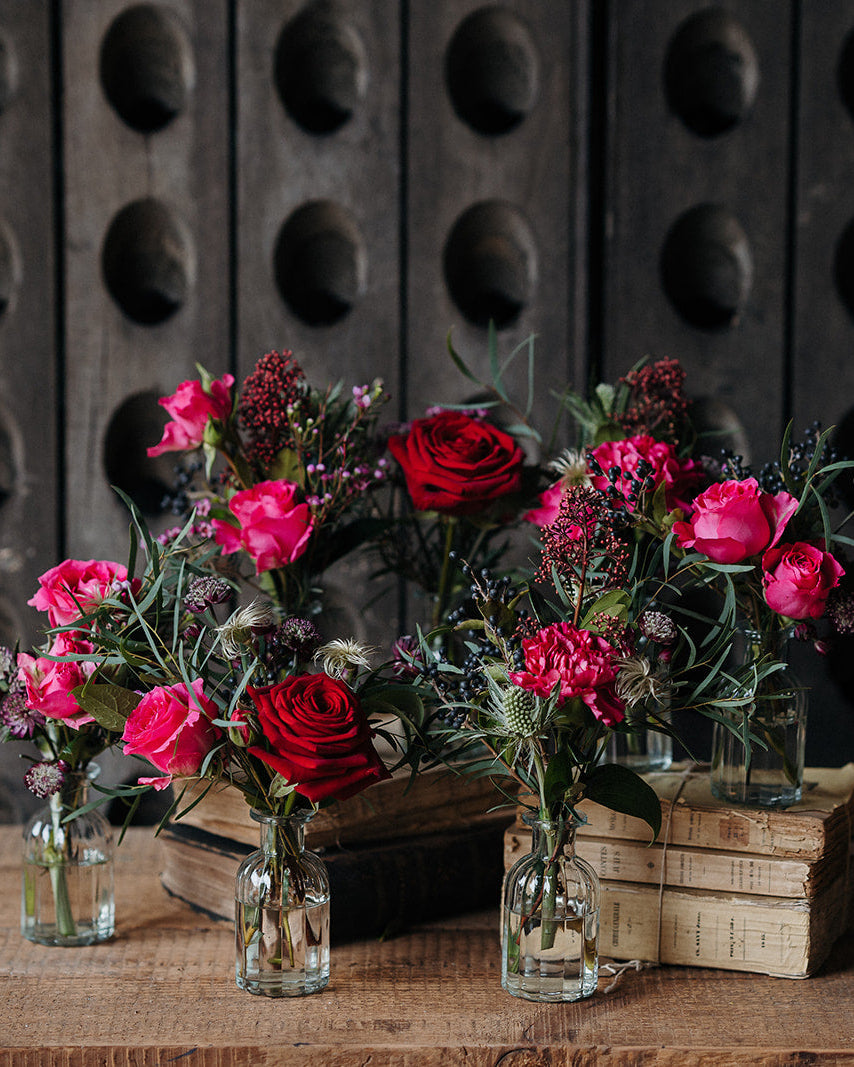 Merry Little Kisses Christmas bud vase collection with red and pink seasonal flowers, berries and winter foliage arranged in individual glass vases