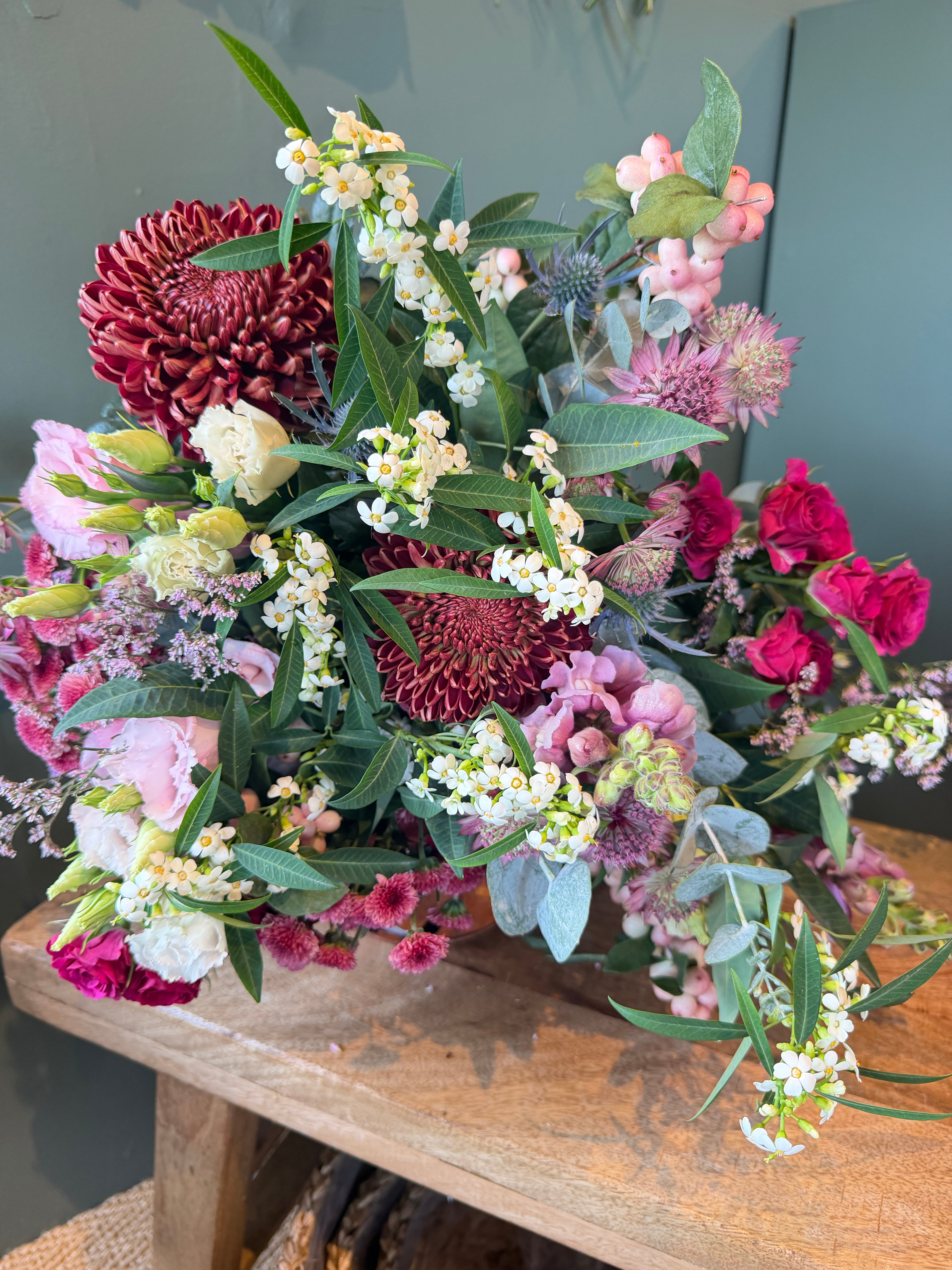 October Bouquet of the Month with burgundy flowers, hot pink roses, snowberry, eryngium and eucalyptus