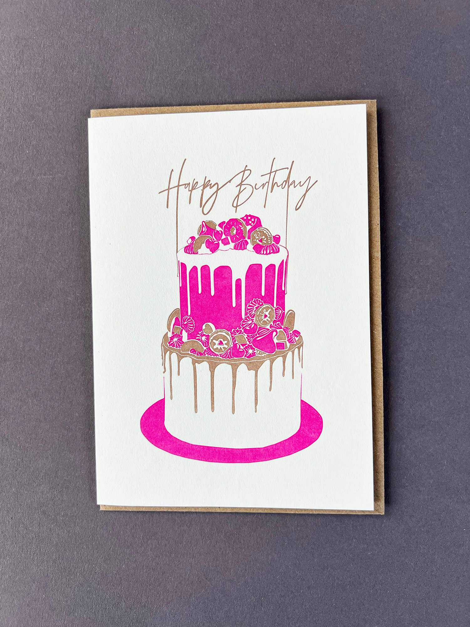 Penguin Ink Birthday Cake letterpress birthday card featuring a neon red two-tier cake, metallic gold details and Happy Birthday calligraphy.