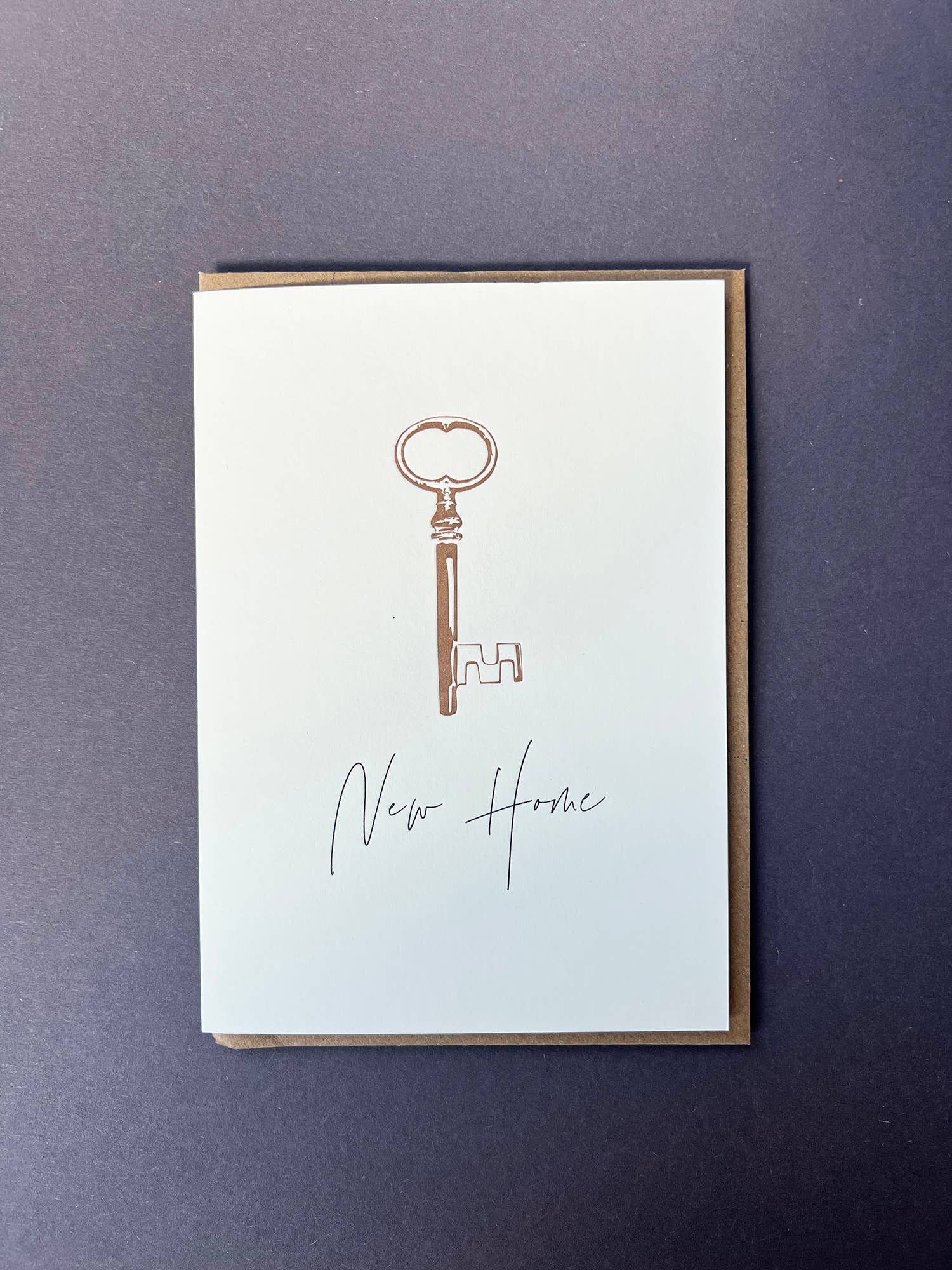 Penguin Ink New Home Key letterpress greeting card featuring a vintage key with metallic gold detailing and modern calligraphy, printed on 100% recycled board with a tactile embossed finish.