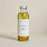 A glass bottle of Plum & Ashby Wild Fig & Saffron bath essence with a label that includes the product name and the text 'Wild Fig & Saffron'.