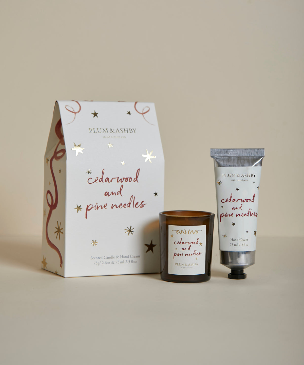 Plum & Ashby Cedarwood & Pine Needles Christmas gift set containing a scented votive candle and matching nourishing hand cream in a presentation box.