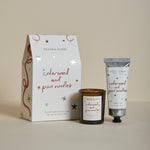 Plum & Ashby Cedarwood & Pine Needles Christmas gift set containing a scented votive candle and matching nourishing hand cream in a presentation box.