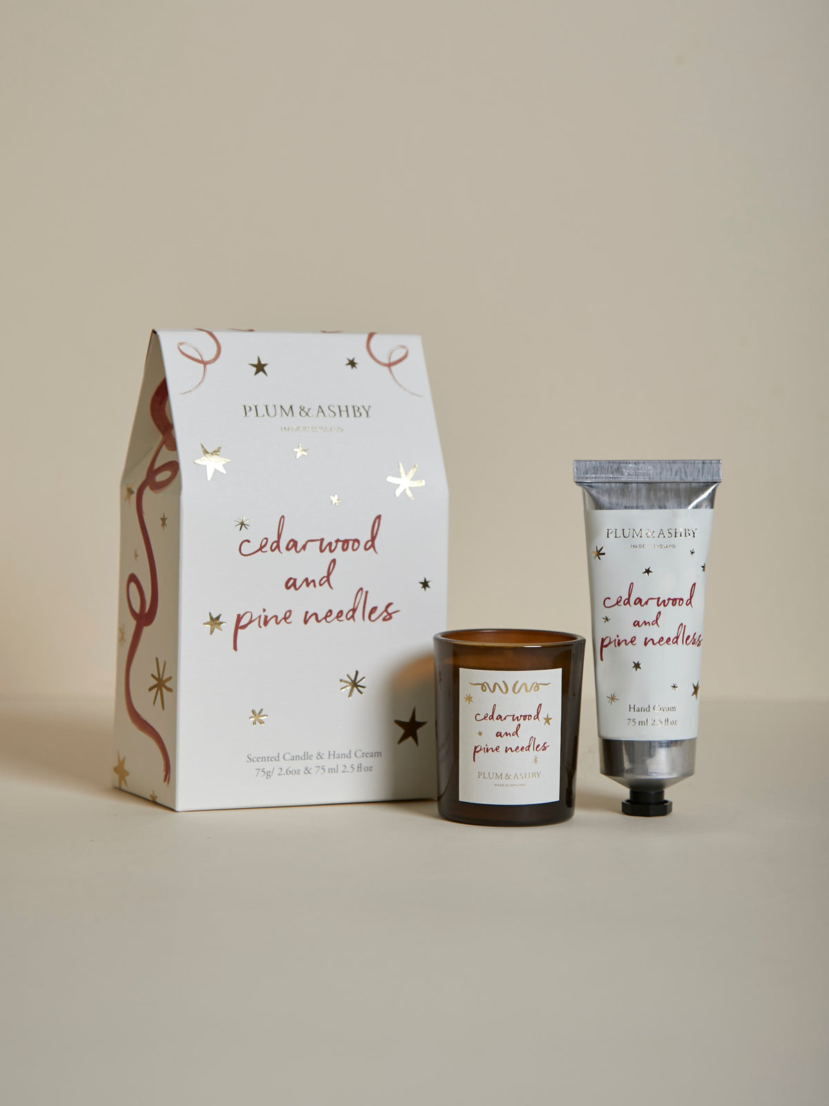 Plum & Ashby Cedarwood & Pine Needles Christmas gift set containing a scented votive candle and matching nourishing hand cream in a presentation box.