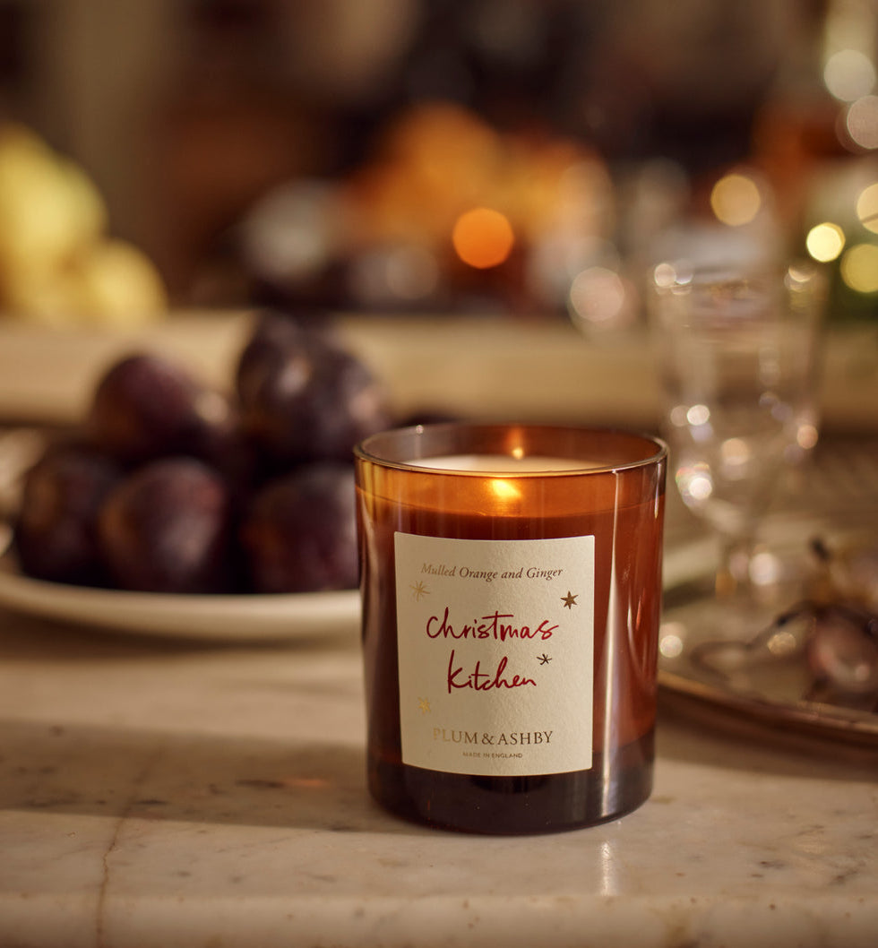 Plum & Ashby Christmas Kitchen Candle in Mulled Orange & Ginger fragrance, presented in amber glass with illustrated festive packaging.