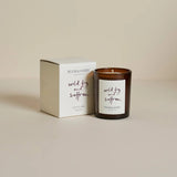 A votive candle with a fig and saffron label in a brown glass container, next to its packaging box with 'Plum & Ashby' branding.