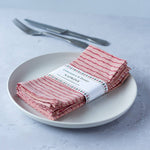 Set of four raspberry and terracotta wiggle line cotton napkins, hand block printed on natural cotton with a playful artisan design.