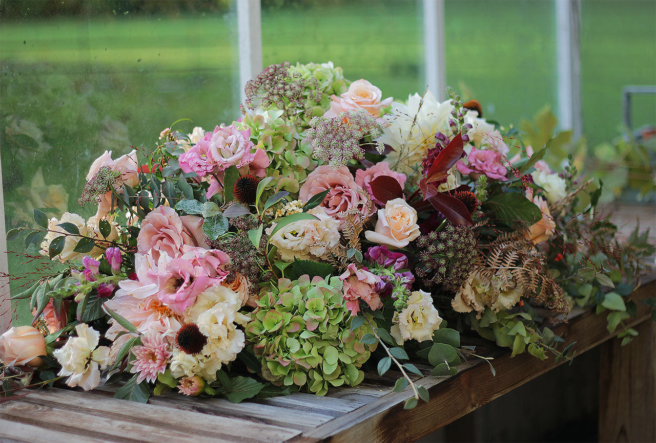 Natural garden-style casket spray funeral flowers featuring seasonal blooms and foliage, handcrafted by Mad Lilies florists in Banstead, Surrey.