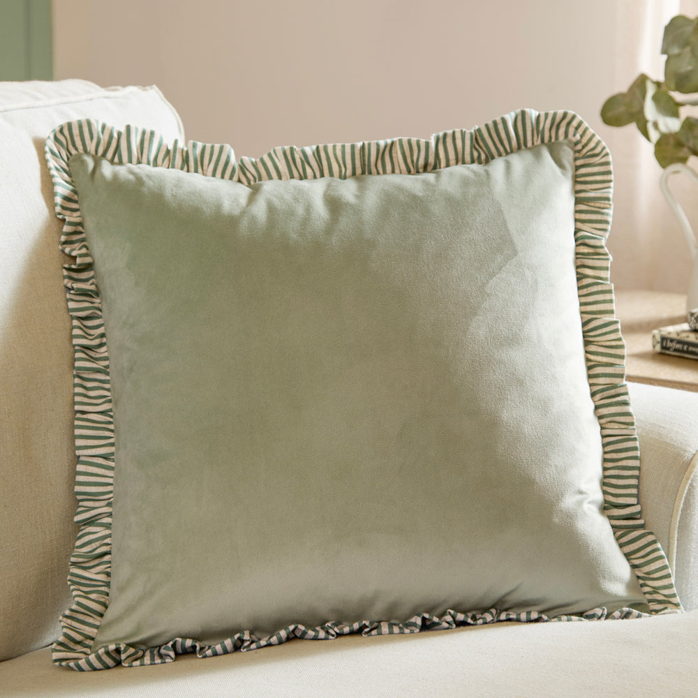 Matte velvet cushion with striped linen-blend ruffle trim. Soft pastel tones with feather or polyester filling. Elegant, textured home décor accent.