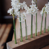 Handcrafted solid oak Flower Stem Keeper with individual glass tubes displaying fresh flower stems in a minimalist wooden vase.