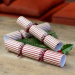 Striped Christmas crackers containing handcrafted wooden Christmas tree decorations