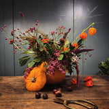 The Autumn Spell autumn pumpkin arrangement by Mad Lilies, featuring orange Chinese lanterns, red rosehips, pink pepperberries and sculptural seasonal foliage.