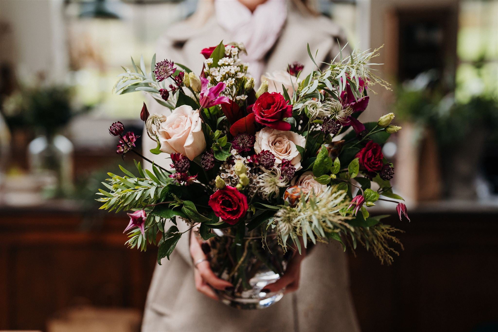 The Christmas Starlet  luxury vase arrangement featuring Quicksand roses, deep red lisianthus, delicate seasonal flowers, winter berries and eucalyptus foliage.