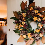 Alt text: The Clementine luxury Christmas door wreath with magnolia, spruce, oranges and velvet ribbon