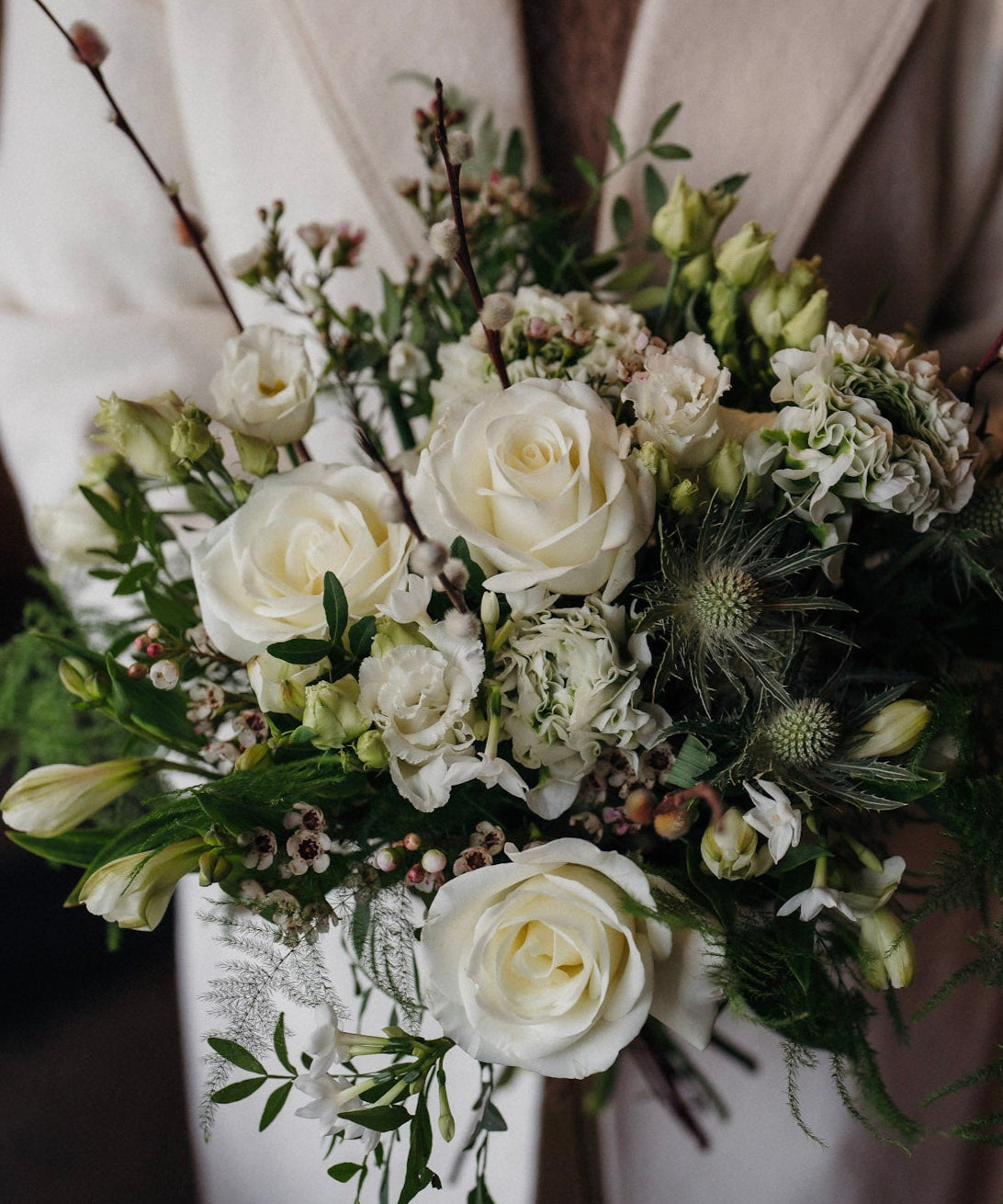 The December white winter flower bouquet with White Tibet roses, lisianthus, waxflower and pussy willow.