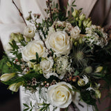 The December white winter flower bouquet with White Tibet roses, lisianthus, waxflower and pussy willow.