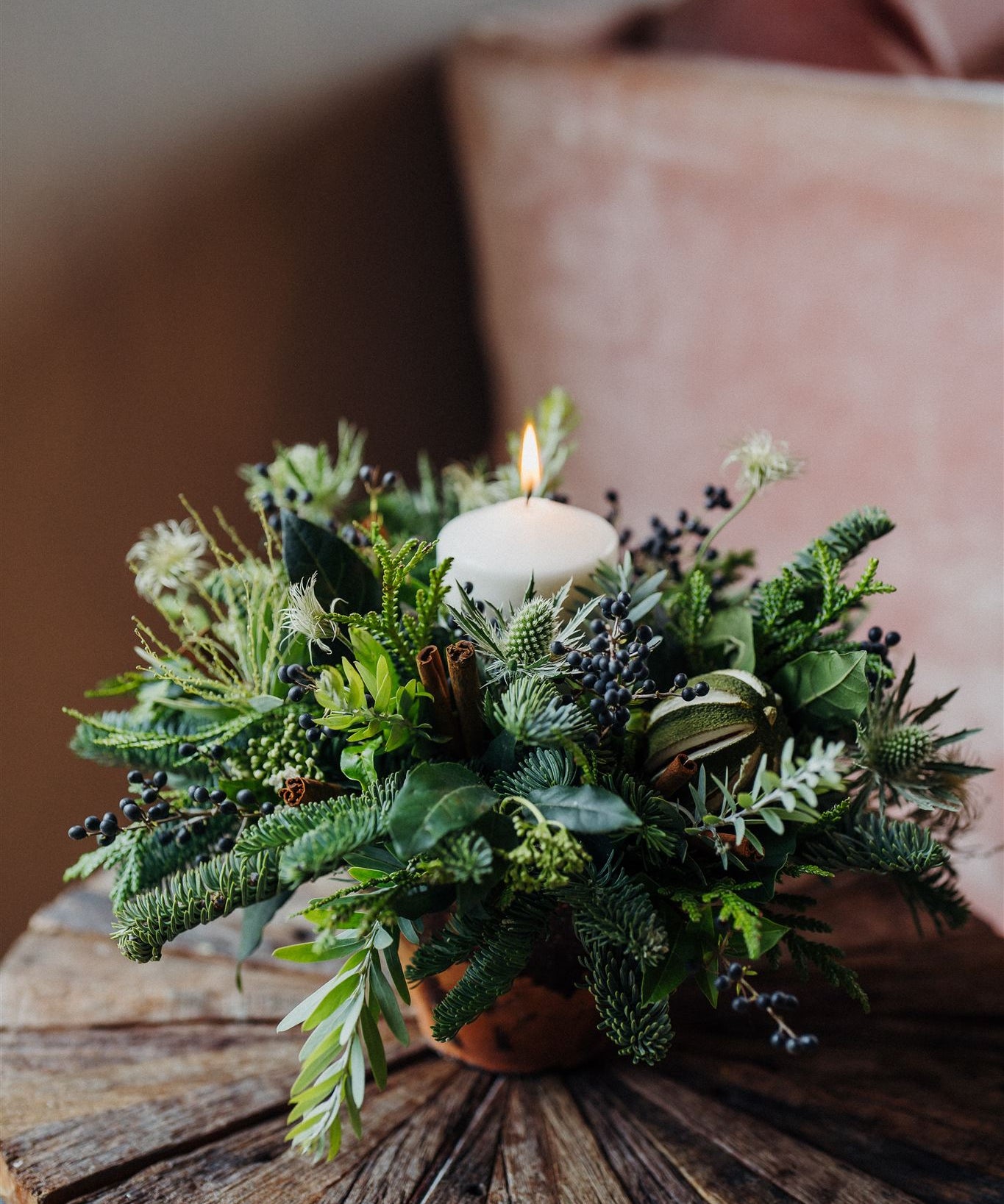 Discover The Enchanted Forest, a Christmas candle centrepiece in aged terracotta with fragrant pine, winter foliage, pinecones, dried limes and a pillar candle.