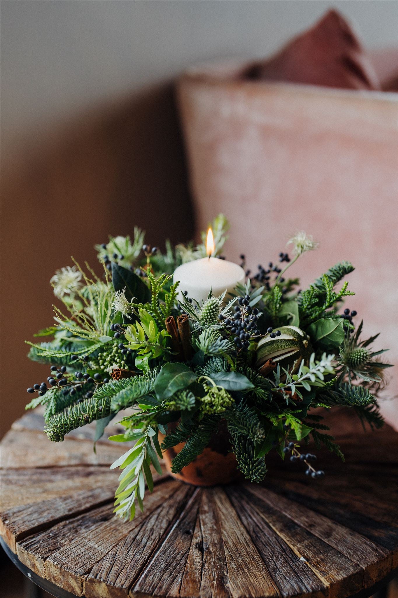 Discover The Enchanted Forest, a Christmas candle centrepiece in aged terracotta with fragrant pine, winter foliage, pinecones, dried limes and a pillar candle.