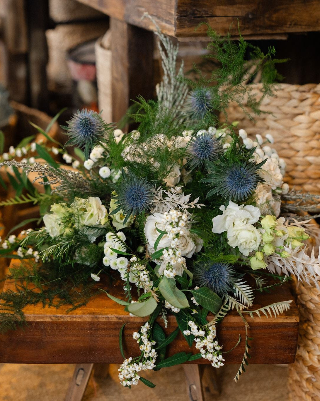 The Highland Mist luxury winter bouquet featuring elegant white Tibet roses, blue-grey thistles, lisianthus, waxflower and pussy willow, hand-tied by Mad Lilies.