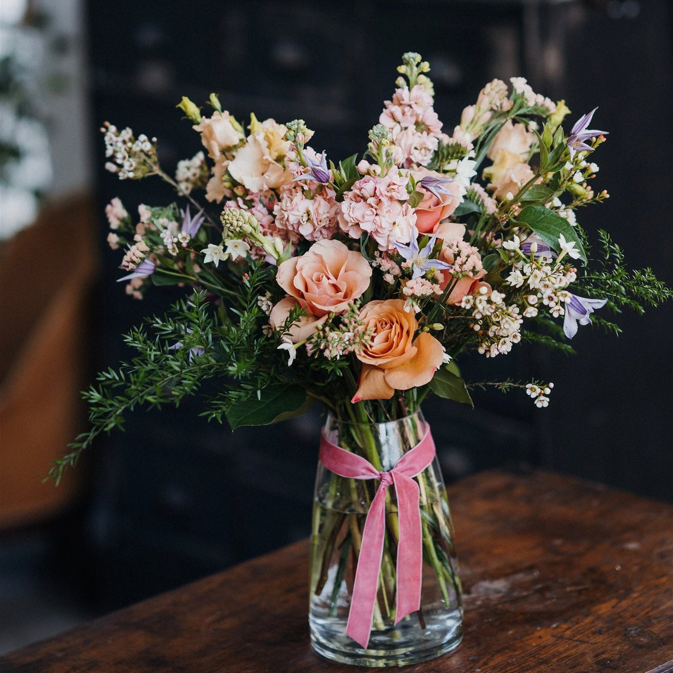 Seasonal flower arrangement in a vase featuring fresh flowers and foliage in a natural garden-inspired style.
