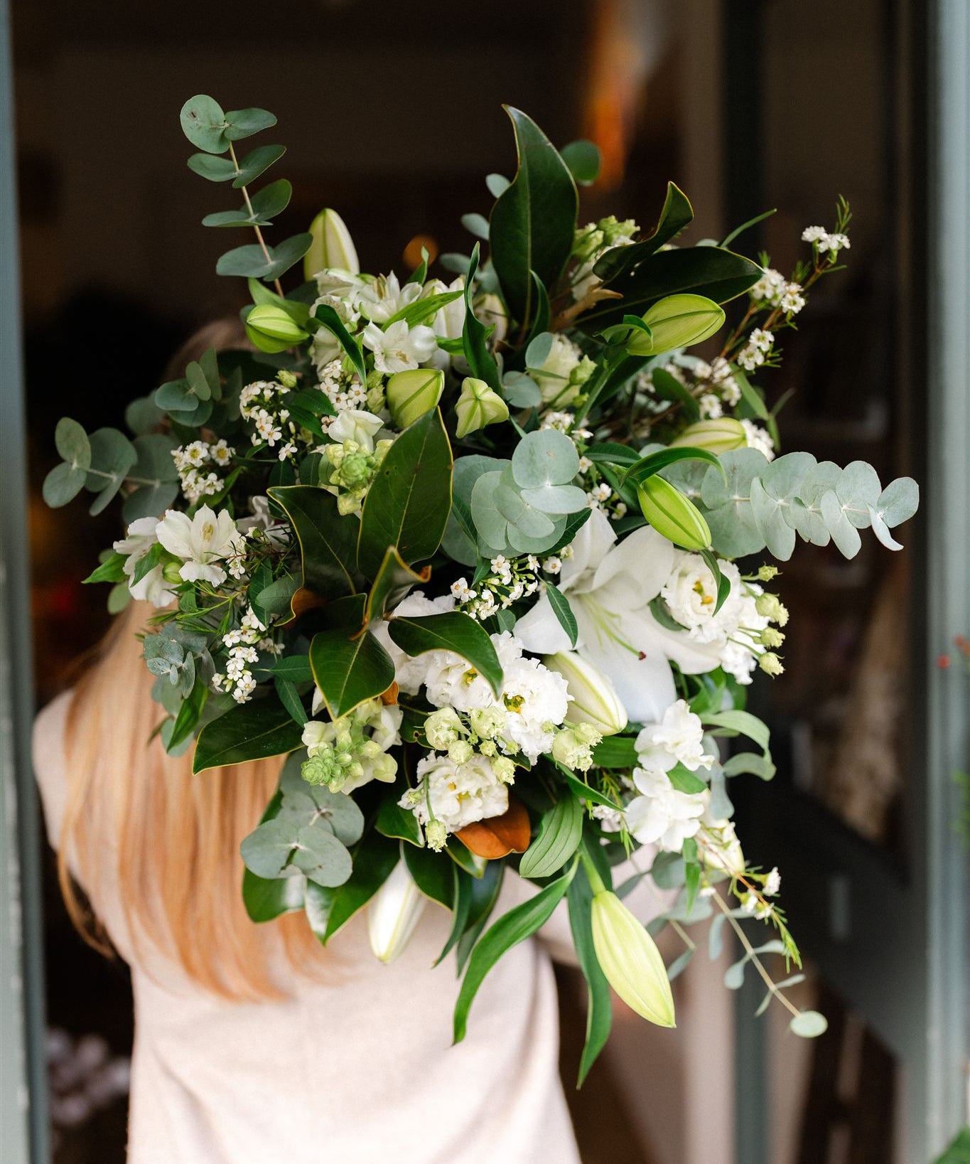 White Oriental lily bouquet with seasonal white flowers and fresh green foliage, hand-tied in a natural garden style.