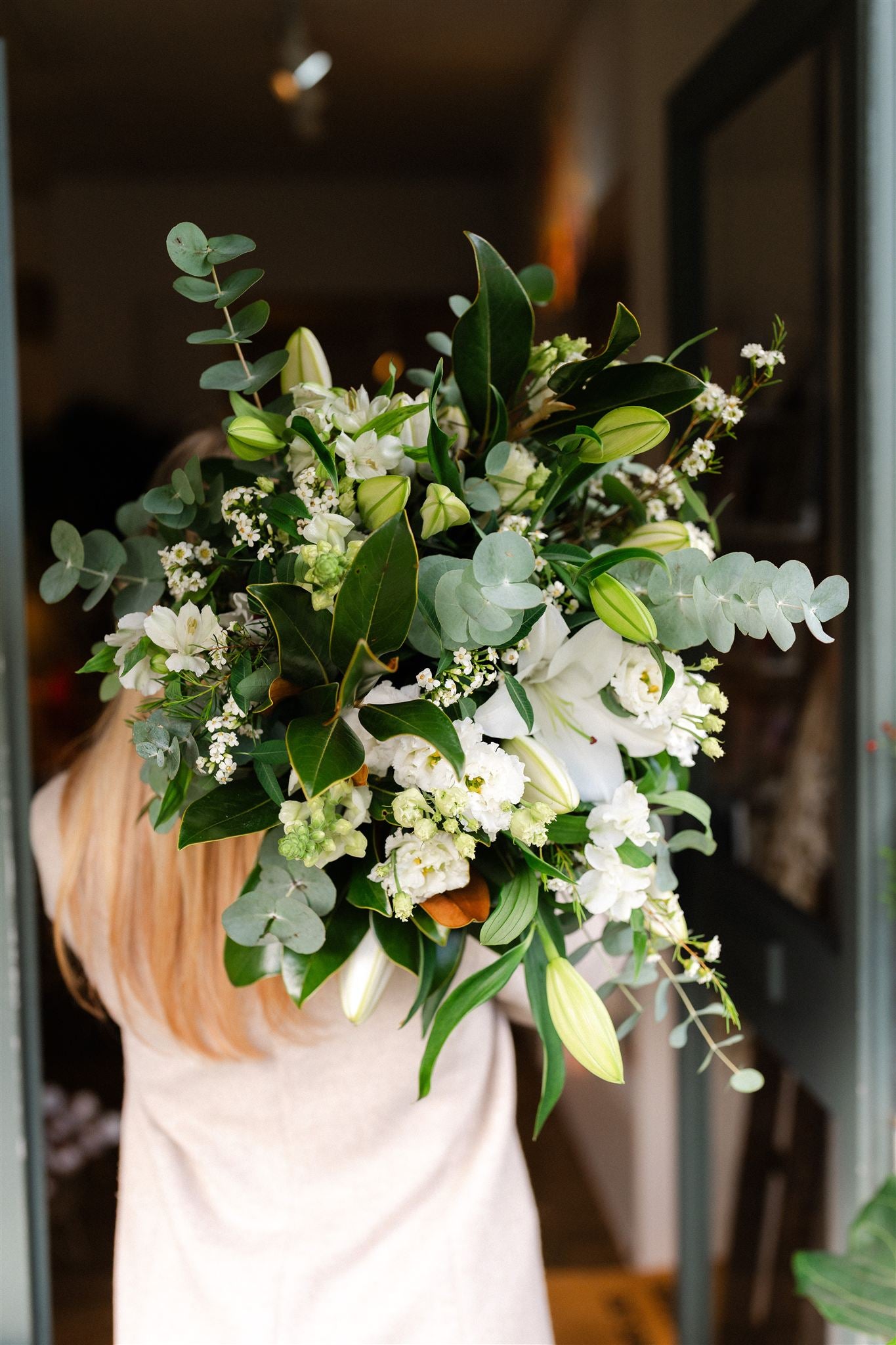 White Oriental lily bouquet with seasonal white flowers and fresh green foliage, hand-tied in a natural garden style.
