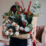 The Nordic Jewel fresh Christmas foliage and winter stem bunch featuring eucalyptus, red Ilex berries, festive pine and soft cotton, wrapped in kraft paper with ribbon.