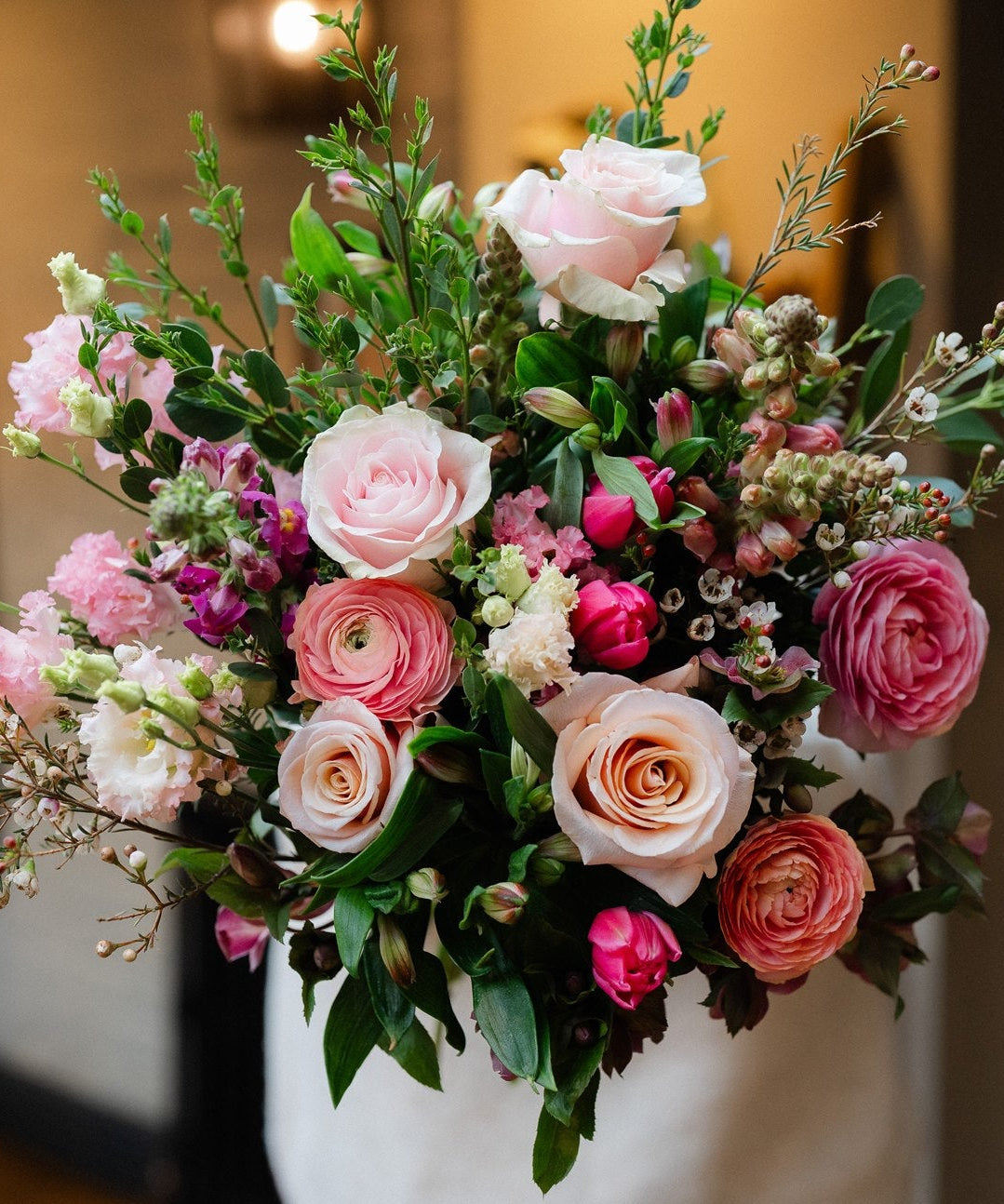 Pink rose bouquet with seasonal flowers and fresh foliage in a romantic garden-inspired style.