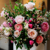 Pink rose bouquet with seasonal flowers and fresh foliage in a romantic garden-inspired style.