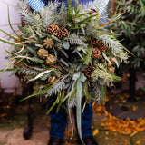 The Wildwood fresh Christmas door wreath with pine, eucalyptus, seasonal green foliage, natural pinecones, dried limes and velvet ribbon.
