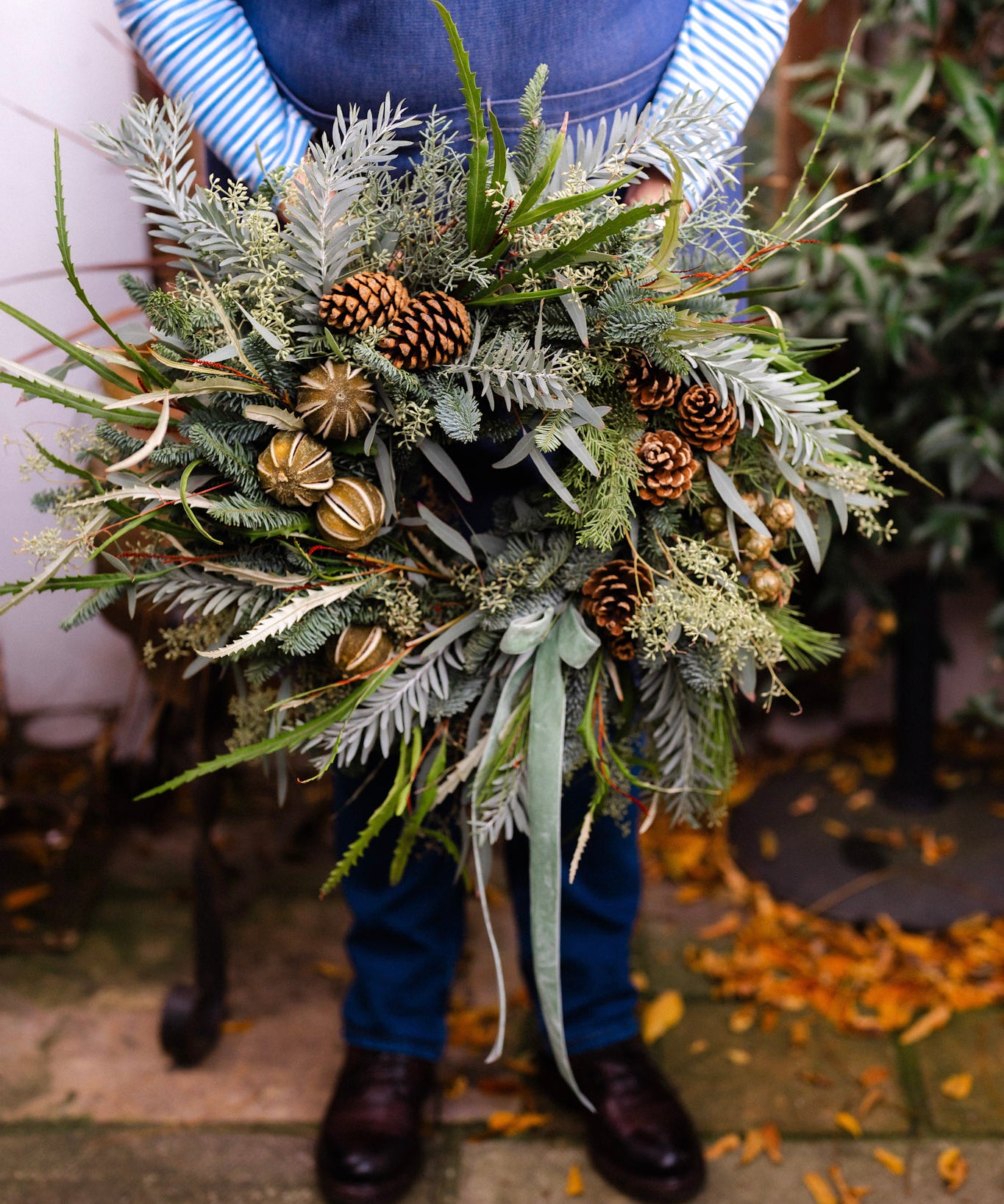 The Wildwood fresh Christmas door wreath with pine, eucalyptus, seasonal green foliage, natural pinecones, dried limes and velvet ribbon.