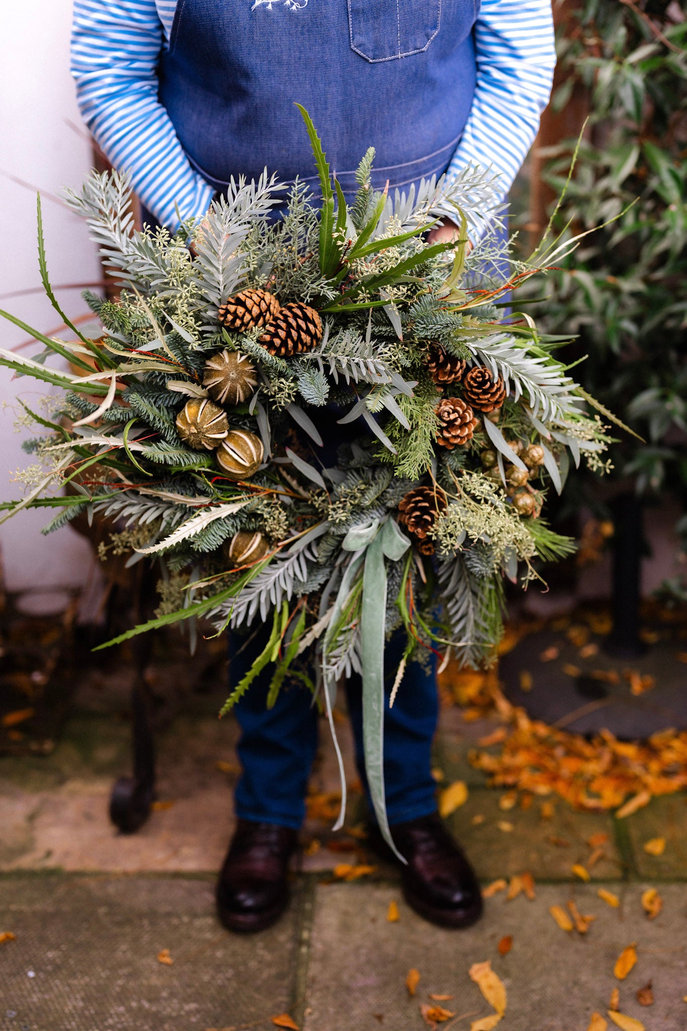 The Wildwood fresh Christmas door wreath with pine, eucalyptus, seasonal green foliage, natural pinecones, dried limes and velvet ribbon.