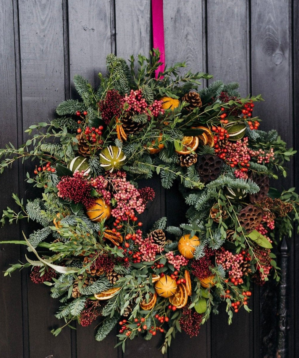 The Winterberry luxury fresh Christmas door wreath with pine, eucalyptus, red skimmia, rosehips, pink pepperberries, pinecones, dried oranges and limes.