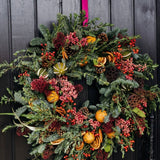 The Winterberry luxury fresh Christmas door wreath with pine, eucalyptus, red skimmia, rosehips, pink pepperberries, pinecones, dried oranges and limes.